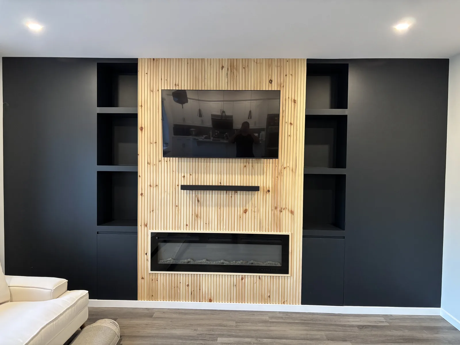 The finished media wall, TV mounted over the fireplace between open shelves