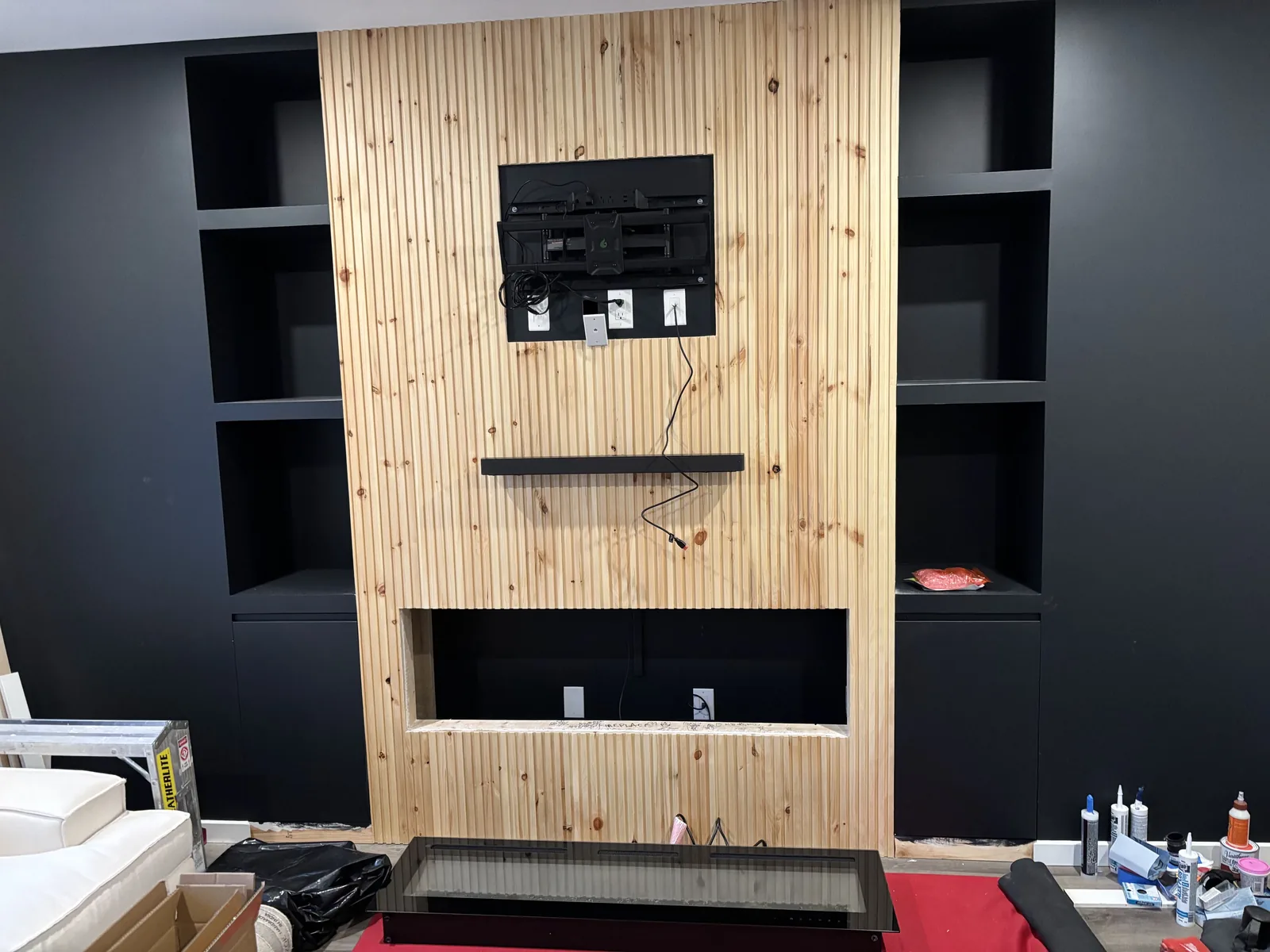 Slat panel and fireplace opening set between the dark built-in cabinets