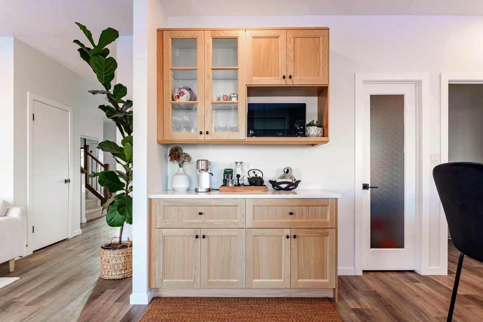 Coffee bar in light wood with glazed uppers and a microwave nook, off the main living space