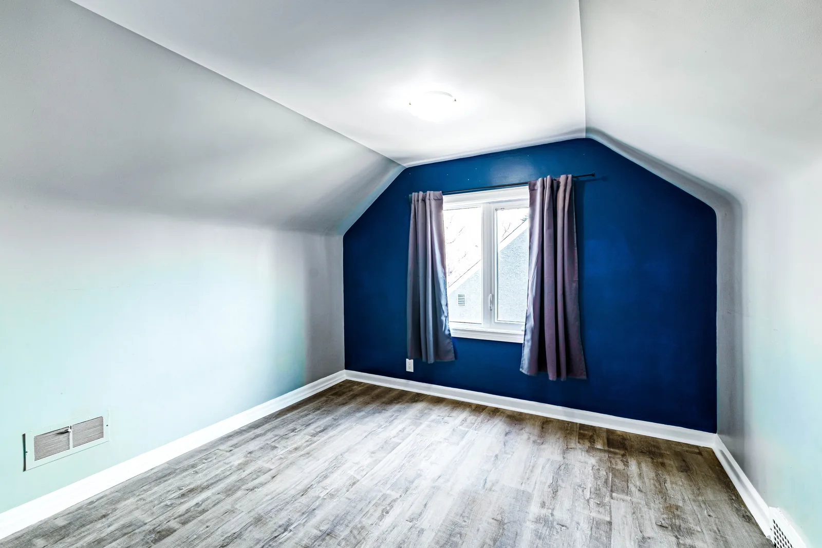 The same bedroom from the door, window dressed against the navy wall