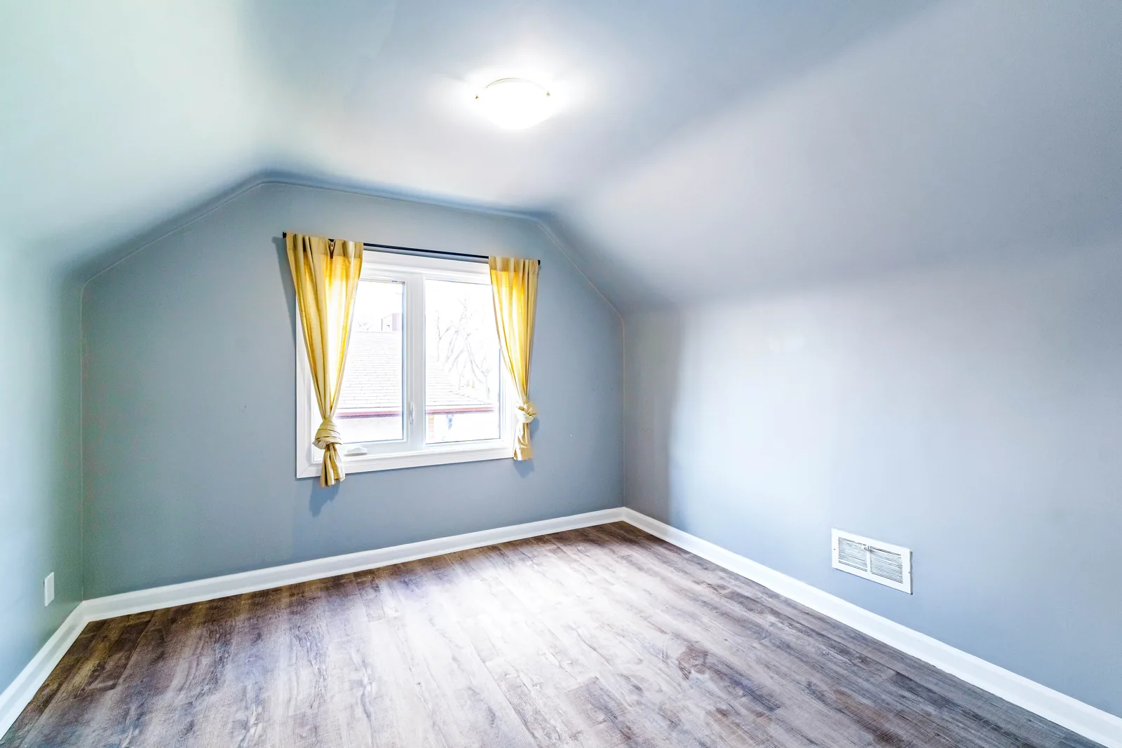 Second bedroom under a sloped ceiling, window onto the street
