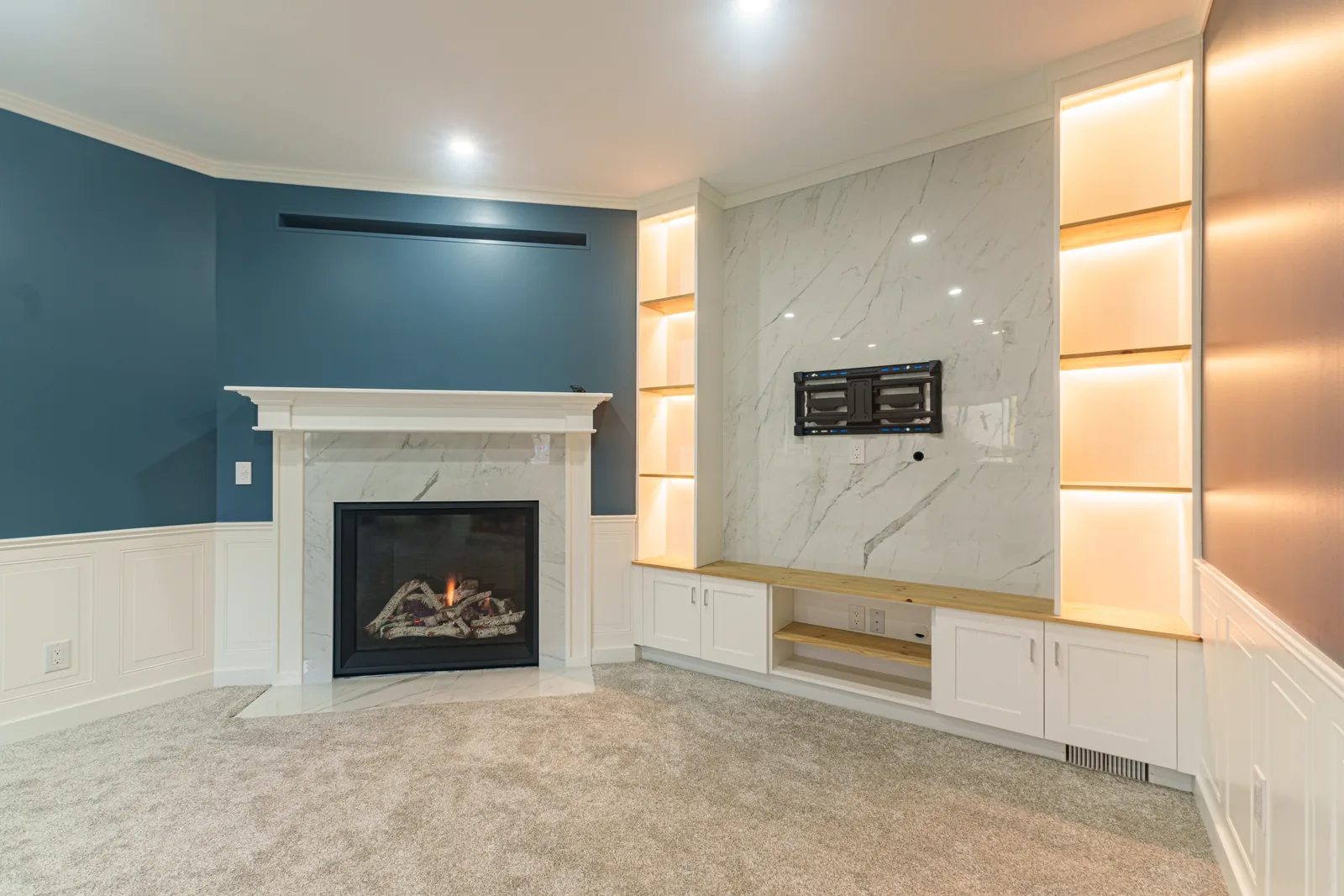 Fireplace wall from the side, lit shelving niches running up beside the mantel