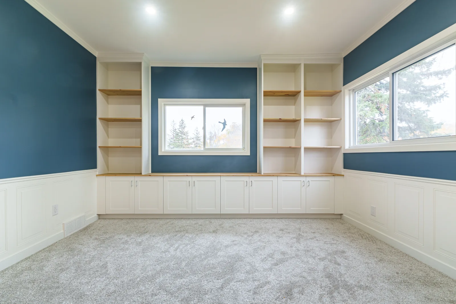 The room end to end, new windows set into the panelled navy wall
