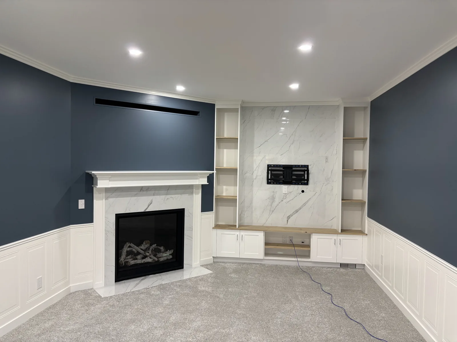 Fireplace and built-ins from across the room, wainscot running the walls