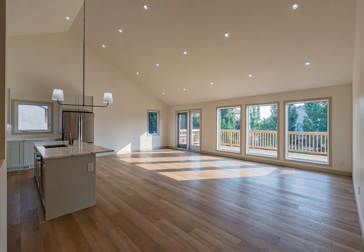 Vaulted great room with white oak floors and a wall of glazed doors to the deck