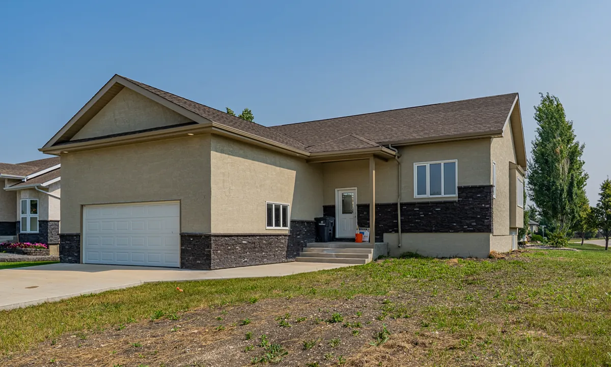 Bungalow with an attached garage, seen from the front across the lot