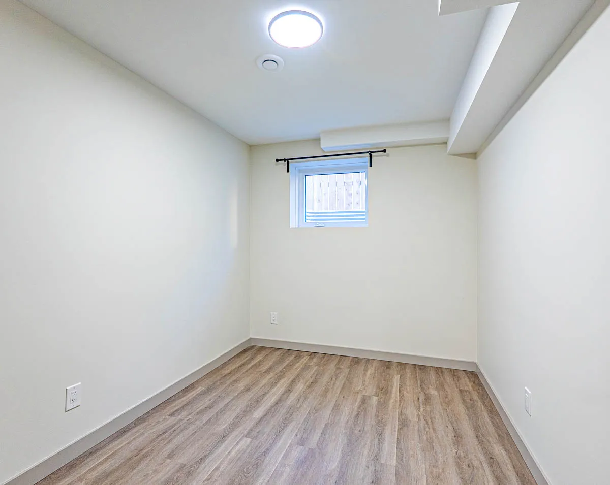 A basement bedroom, the window high on the far wall