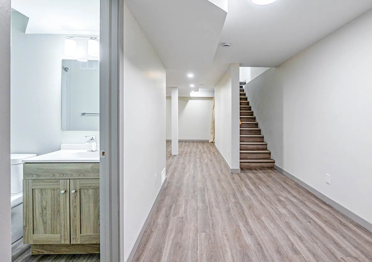 The basement hall, a bathroom to one side and the stair up