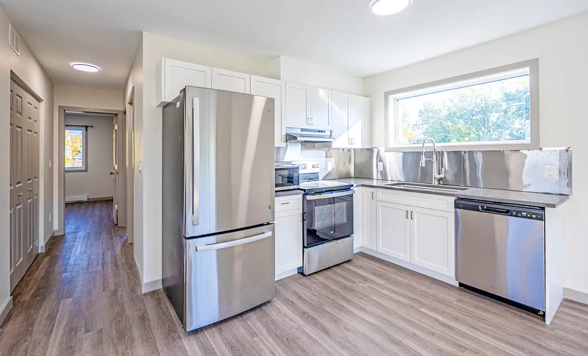 The second kitchen, white shaker cabinetry under a wide window