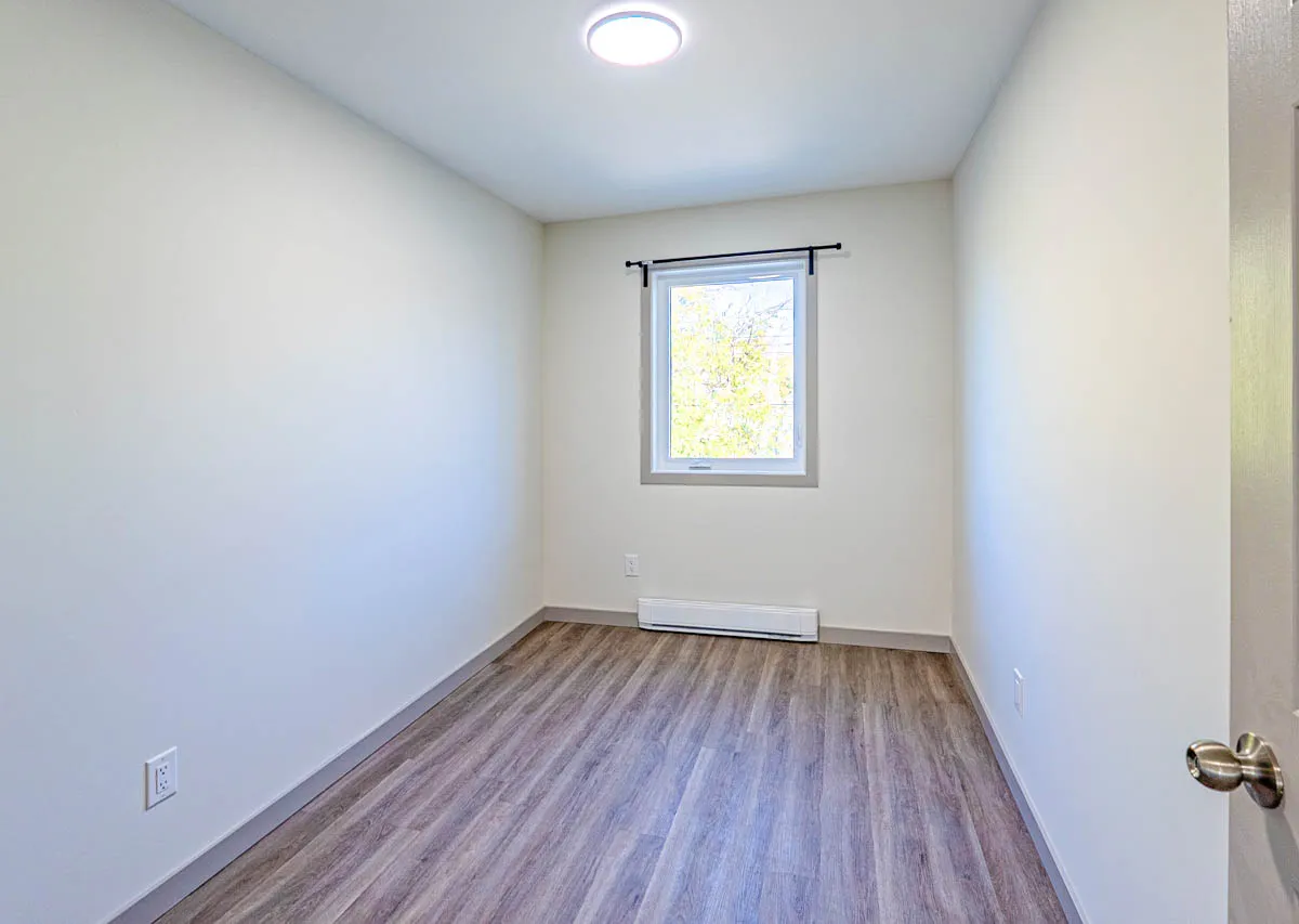 A smaller bedroom with a window on the far wall