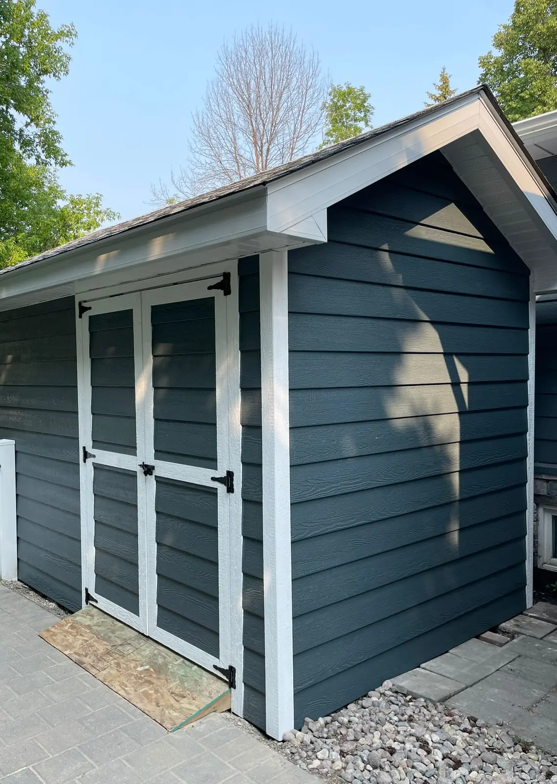 The gable end from the paver path, white corner boards and fascia against the teal