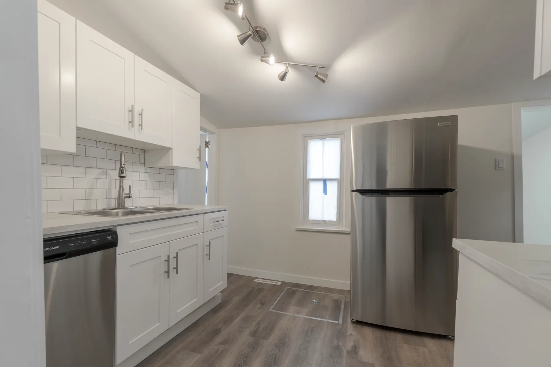 Suite kitchen in white shaker cabinetry with a subway backsplash and stainless appliances