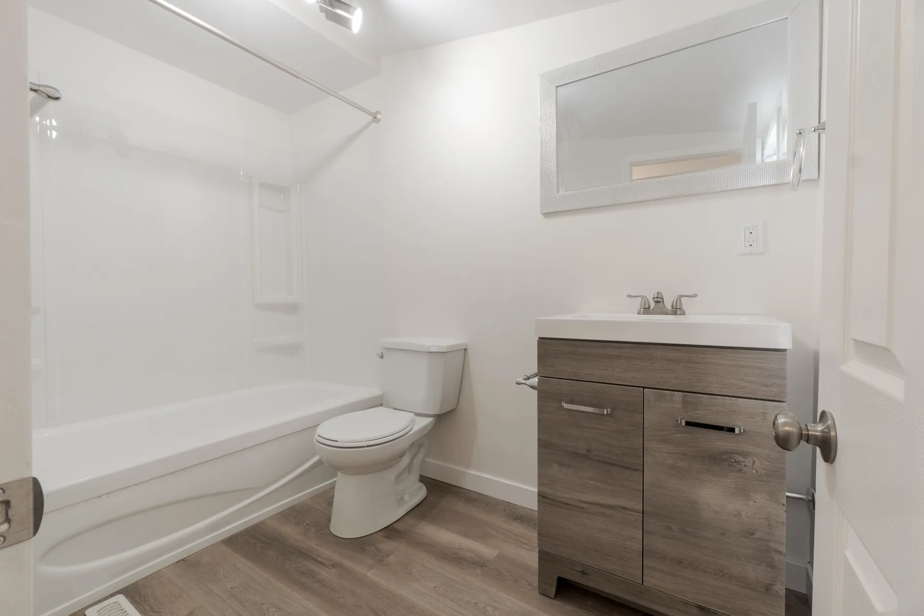 Bathroom with a new tub, wood-front vanity and a recessed niche