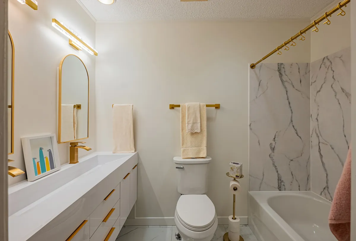 First bathroom from the door, vanity, toilet and tub in white and gold