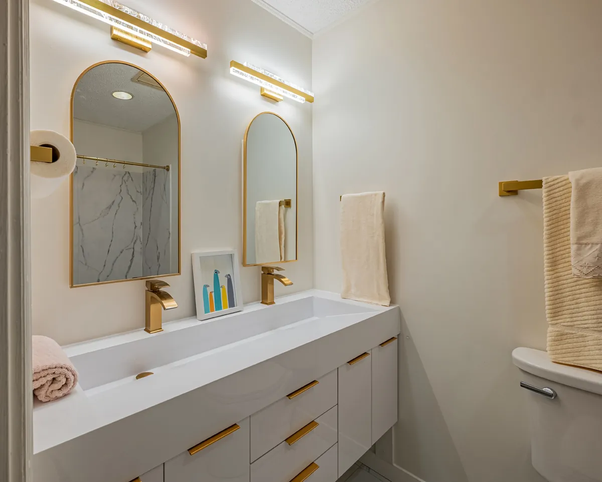 First bathroom vanity, gold taps and light bars over the arched mirrors