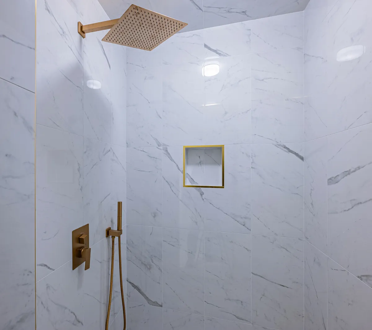 The walk-in shower's square gold rain head and hand shower