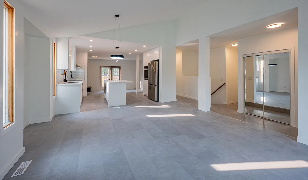 The whole main floor of a renovated home, kitchen at the far end and the stair beyond