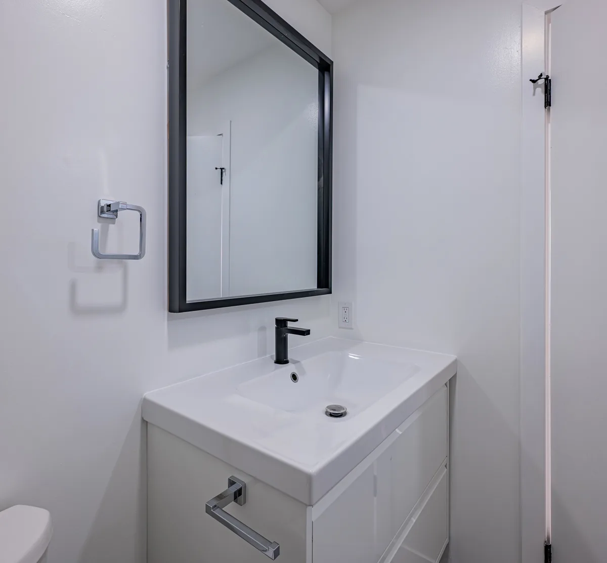 The second bathroom's vanity under a black-framed mirror