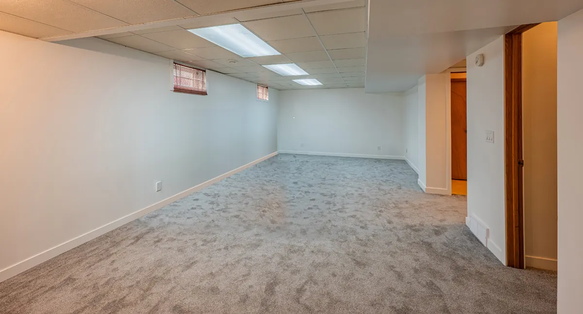 The finished basement, new carpet laid wall to wall under white walls