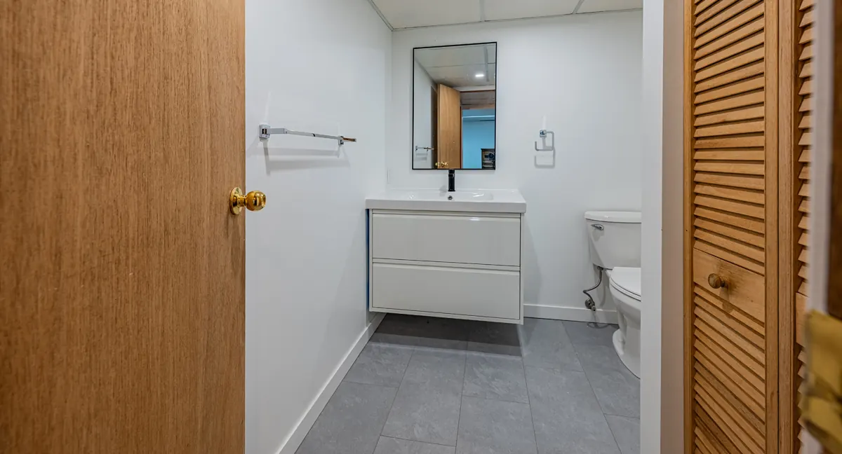 Basement bathroom with a floating white vanity and a black-framed mirror