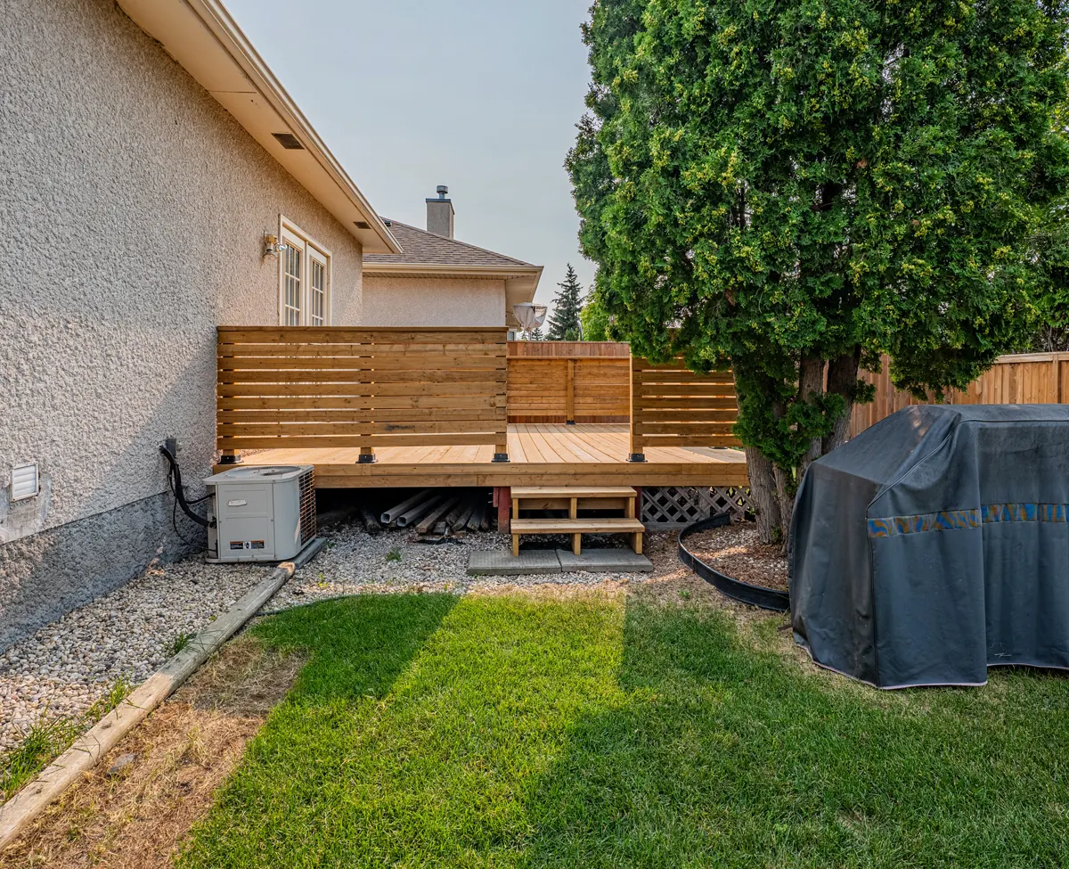 The deck from the yard, a horizontal-slat screen along its edge