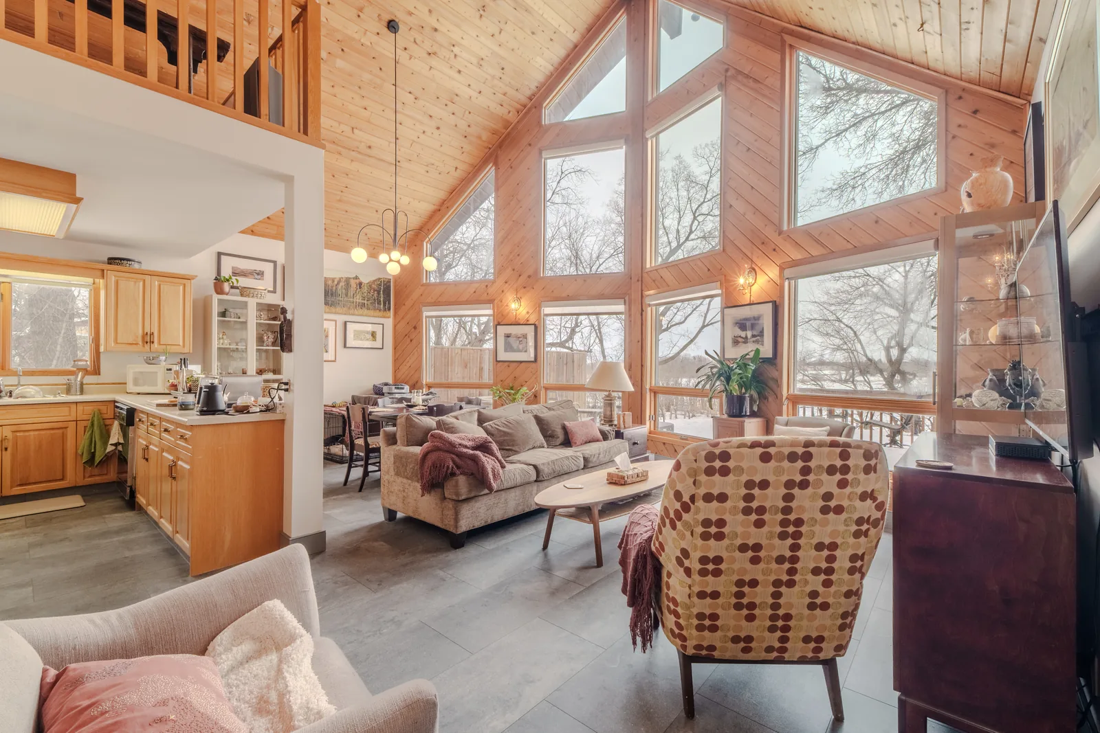 Vaulted living room in cedar, a wall of windows onto the woods