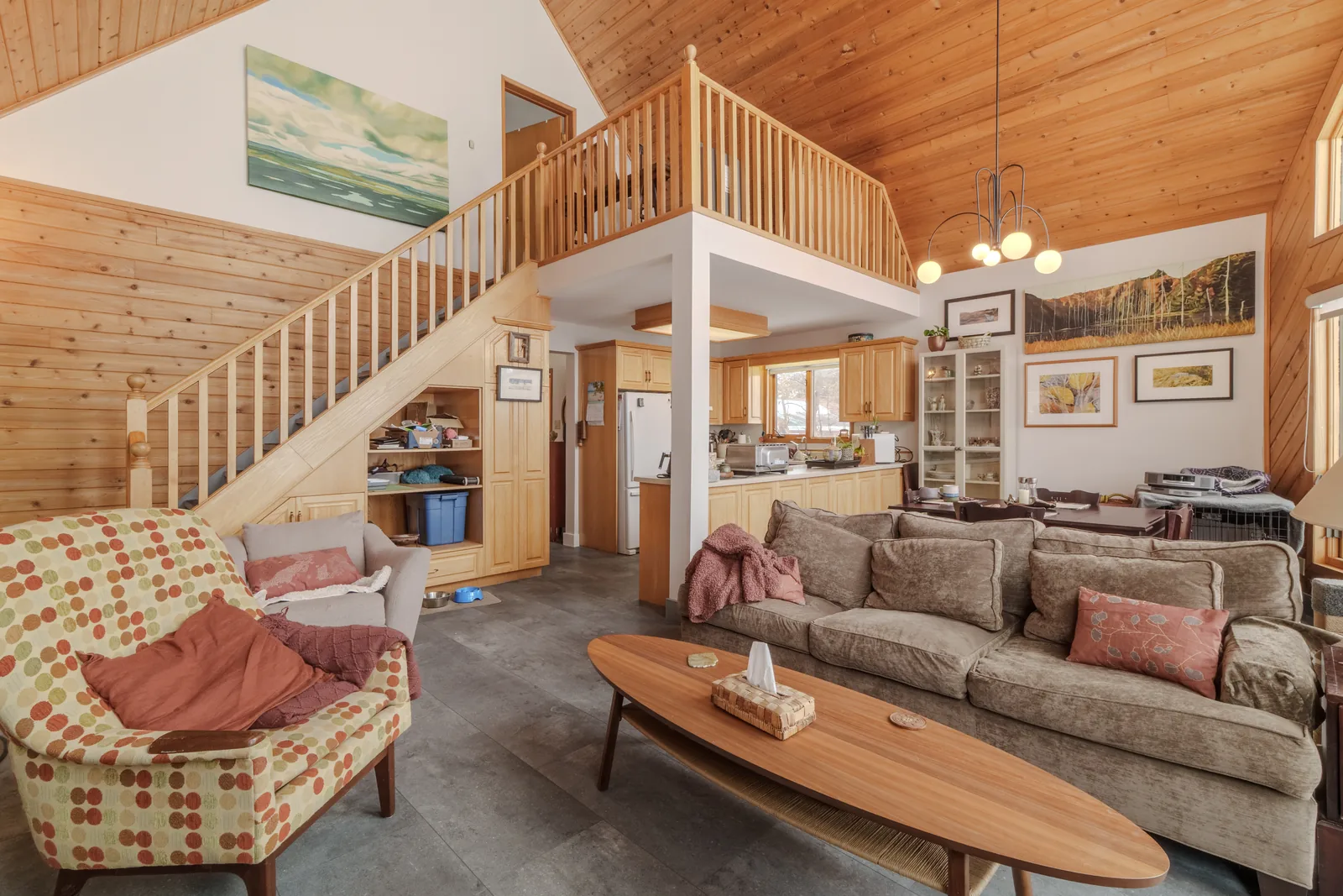The living room and its loft rail, stair climbing the timber wall