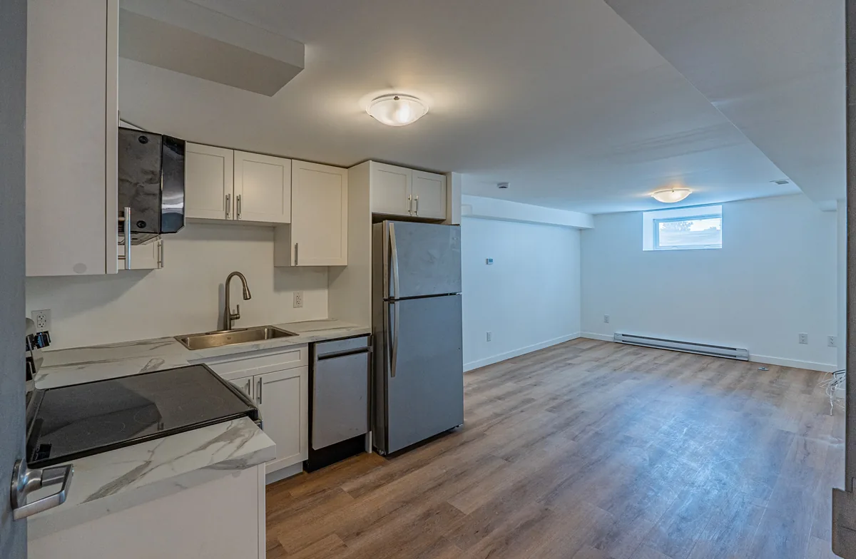 Kitchen opening onto the living area, plank flooring laid throughout