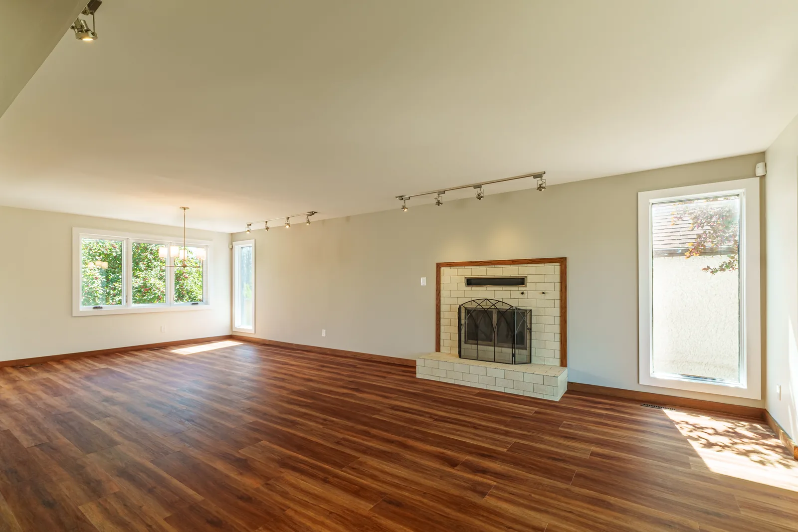 Open main floor after refinishing — new plank flooring running through to the kitchen