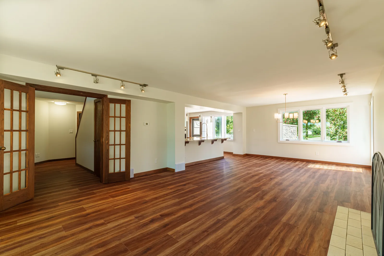 Living and dining seen as one room, track lighting along the vaulted ceiling
